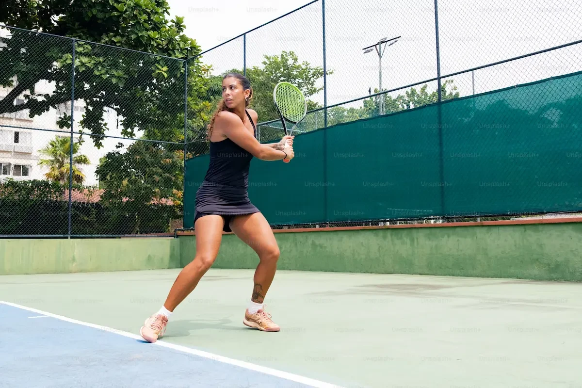 vrouw staat klaar om tenisbal terug te slaan